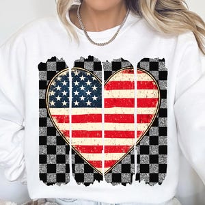 May include: White sweatshirt with a distressed American flag heart design on a checkered background.