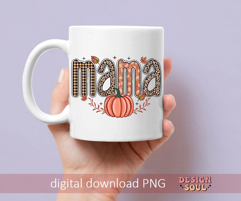May include: White ceramic mug with a fall-themed design. The word "mama" is written in a colorful font with a pumpkin and leaves.