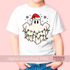 May include: A white t-shirt with a cartoon ghost wearing a Santa hat and Christmas lights. The ghost is white with black eyes and a red Santa hat with green holly. The Christmas lights are red, green, and yellow.