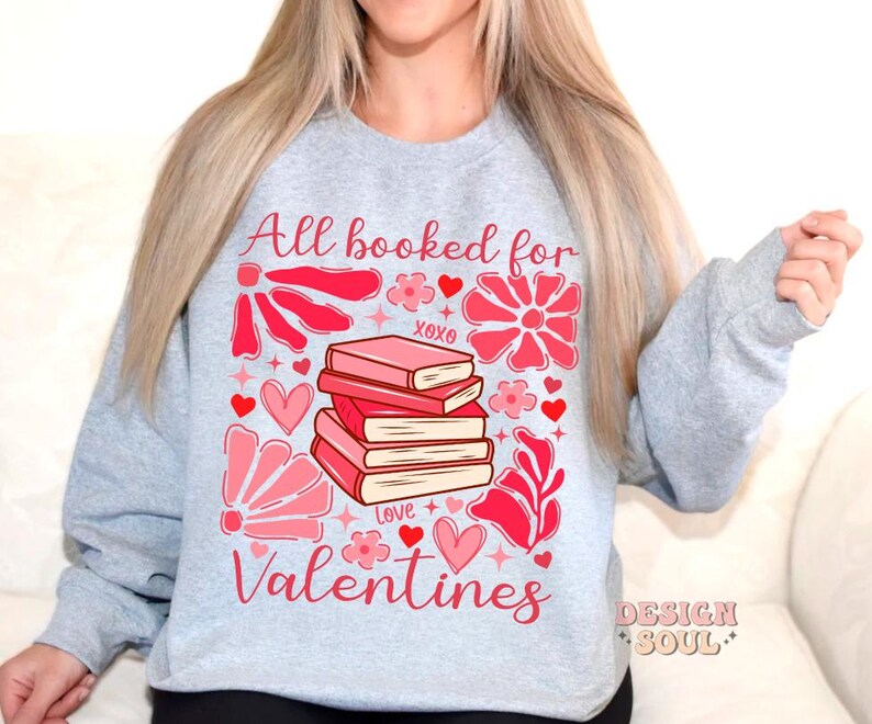 May include: Gray sweatshirt with a pink and red graphic design featuring a stack of books with the text "All booked for Valentines".