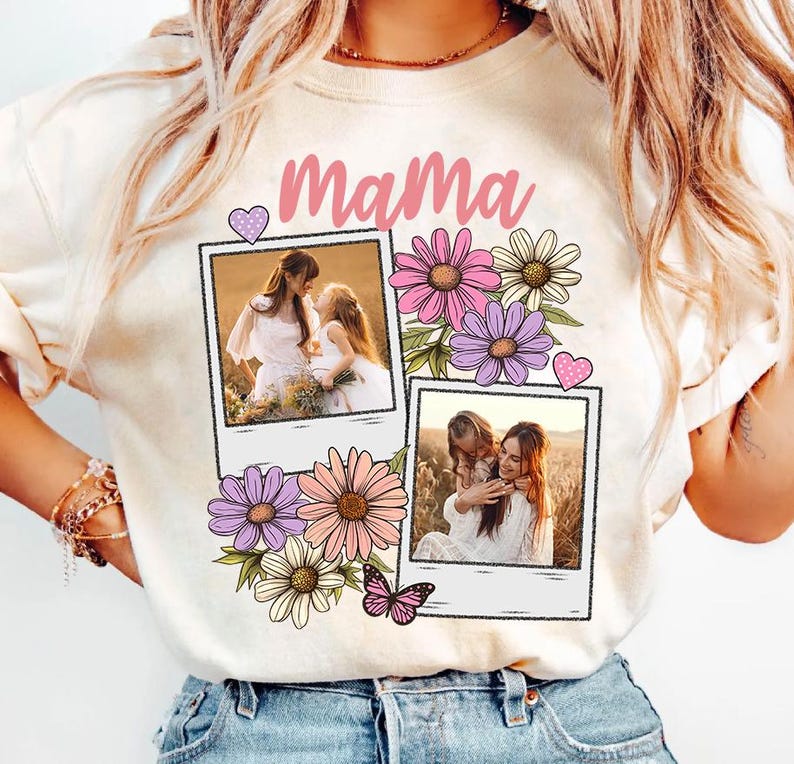 May include: Cream-colored sweatshirt with the word "Mama" in pink script. The design includes two polaroid-style photos, pink and purple flowers, a pink butterfly, and a pink heart.