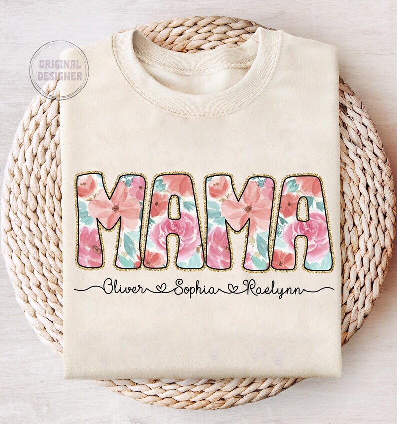 May include: A beige sweatshirt with the word "MAMA" in large, pink floral letters. The names "Oliver", "Sophia", and "Raelynn" are written below the word "MAMA" in a cursive font.