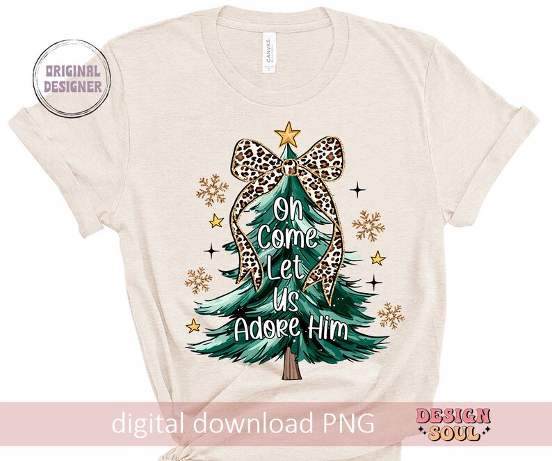 May include: A beige t-shirt with a green Christmas tree design. The tree is decorated with a leopard print bow and the words "Oh Come Let Us Adore Him".