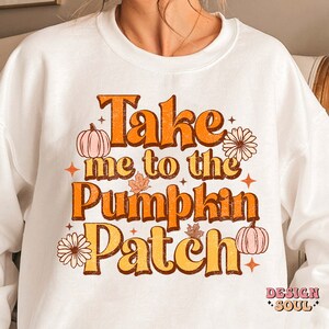 May include: White sweatshirt with a graphic print that says "Take me to the Pumpkin Patch" in orange, brown, and white text with fall-themed illustrations.