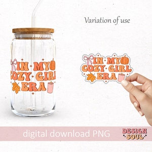 Puede incluir: Una descarga digital de una pegatina con el texto "In My Cozy Girl Era" en una fuente retro. La pegatina presenta una calabaza, una vela, una hoja y un lazo. La pegatina se muestra en una botella de vidrio transparente con una pajita.