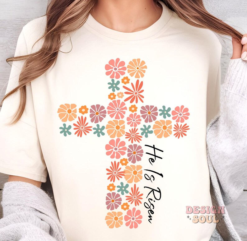 May include: A white t-shirt with a floral cross design and the text "He is Risen" in black lettering.