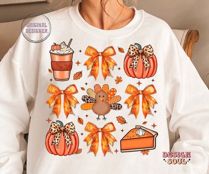 May include: White sweatshirt with a Thanksgiving theme featuring a pumpkin, a turkey, a pie, a coffee cup, and bows. The design is in orange, brown, and black.