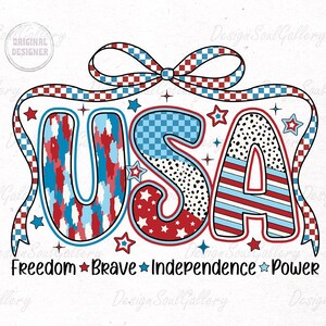 Peut inclure: Un graphique USA rouge, blanc et bleu avec un n&oelig;ud &agrave; carreaux. Les lettres sont d&eacute;cor&eacute;es de diff&eacute;rents motifs, notamment des &eacute;toiles, des rayures et des pois. Le texte ci-dessous indique "Freedom Brave Independence Power".