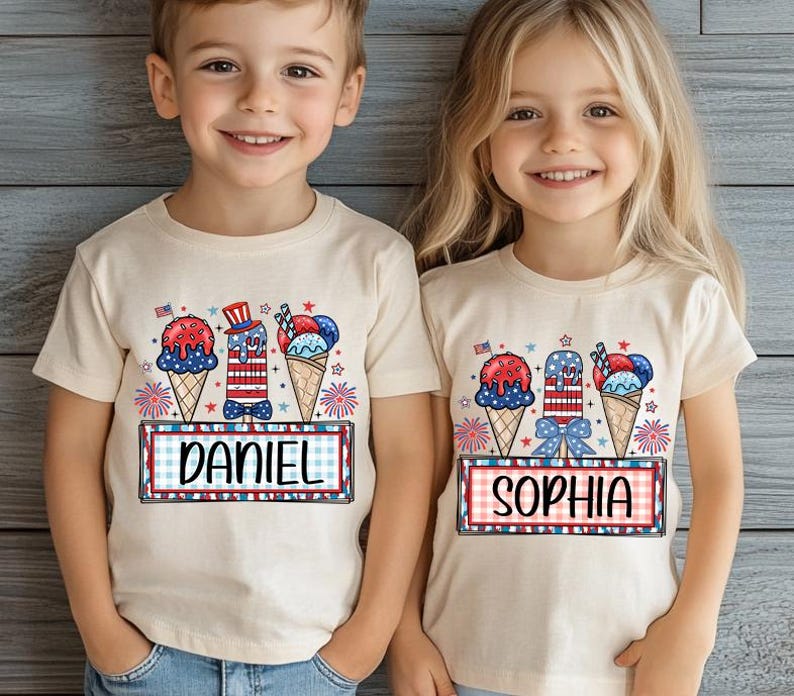 May include: Two children wearing cream-colored t-shirts with a patriotic ice cream design. The design includes ice cream cones, a popsicle, and the names "DANIEL" and "SOPHIA" in a red, white, and blue color scheme, perfect for a 4th of July celebration.