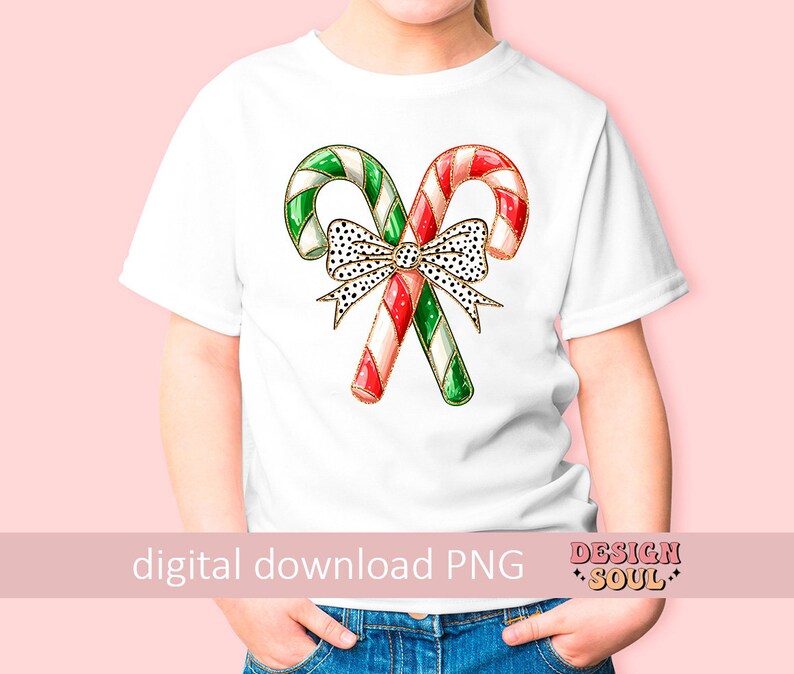 May include: White t-shirt with a red and green candy cane design and a black and white polka dot bow. The candy canes are decorated with gold glitter.