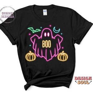 May include: Black t-shirt with a neon pink ghost with the word "BOO" inside. The ghost is surrounded by neon yellow stars, a crescent moon, and two pumpkins.
