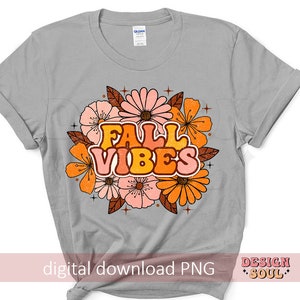 May include: A grey t-shirt featuring a floral design and the text "Fall Vibes" in orange, yellow and pink.