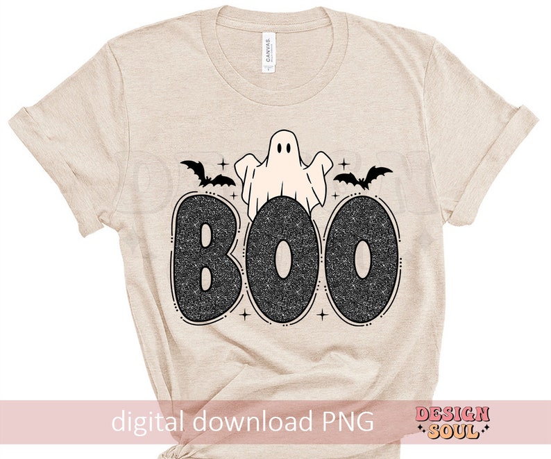 May include: A beige t-shirt with a black and white graphic of a ghost and bats with the word "BOO" in sparkly letters.