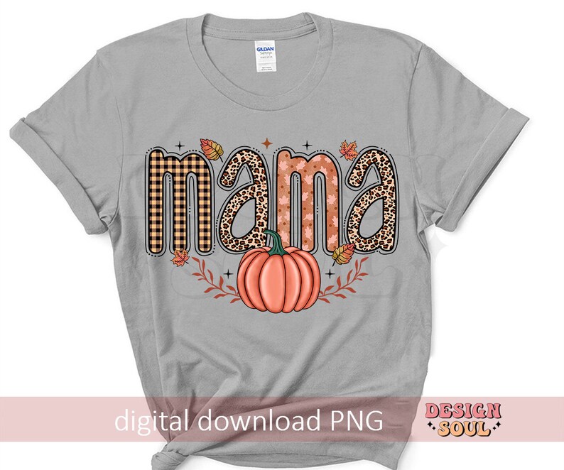 May include: A gray t-shirt with the word "mama" in a fall-themed design. The letters are decorated with plaid, leopard print, and fall leaves. A pumpkin is in the center of the design.