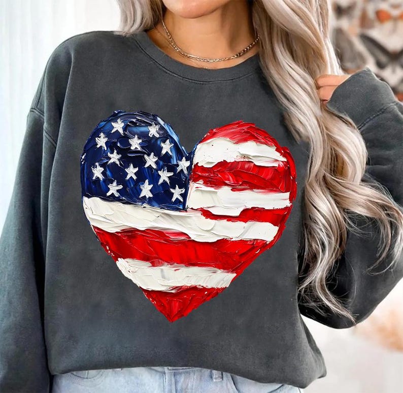 Pu&ograve; includere: Una felpa grigia scura con un design a forma di cuore della bandiera americana dipinto. La bandiera &egrave; rossa, bianca e blu.