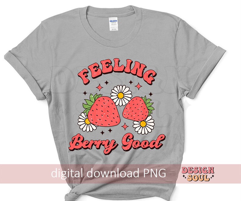May include: A gray t-shirt with the text "Feeling Berry Good" in a retro font. The text is surrounded by a design of two red strawberries with green leaves and white flowers.