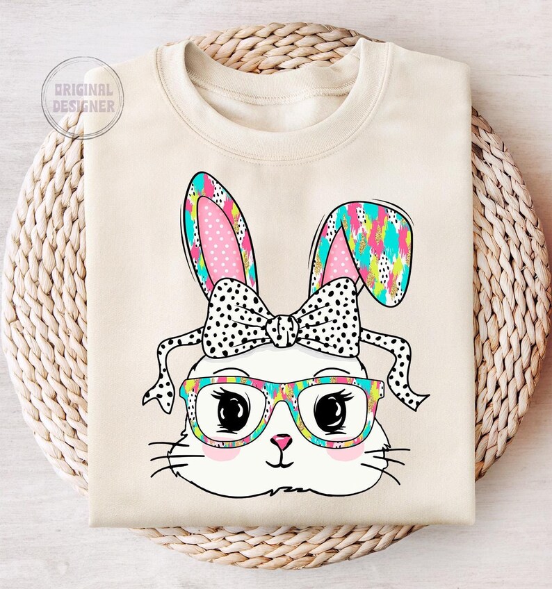 May include: A white bunny with pink ears and a black and white polka dot bow. The bunny is wearing colorful glasses and has a colorful abstract pattern on its ears.