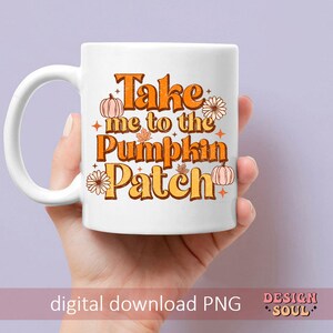 May include: White ceramic mug with a handle. The mug has a graphic design with orange, yellow, and brown colors. The text on the mug reads "Take me to the Pumpkin Patch".