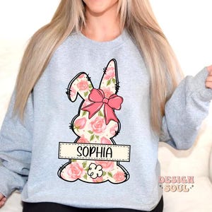 May include: A light gray sweatshirt with a floral bunny design and the name "Sophia" printed on a banner below the bunny.
