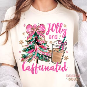 May include: A white t-shirt with a pink and gold Christmas tree, a pink bow, and a cup of coffee. The text "Jolly and Caffeinated" is written in pink letters.