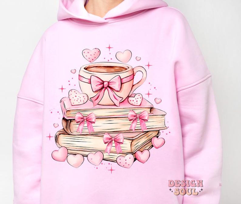 K&ouml;nnte beinhalten: Rosafarbener Hoodie mit einem Motiv aus einer Tasse Kaffee, einem Stapel B&uuml;chern und Herzen. Der Text "Design Soul" ist in der rechten unteren Ecke des Hoodies gedruckt.