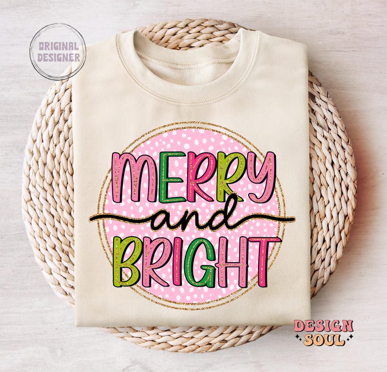 May include: A cream-colored sweatshirt with the words "MERRY and BRIGHT" in pink, green, and black lettering. The text is inside a pink polka-dotted circle with a gold glitter outline. The words "Original Designer" and "Design Soul" are also visible.