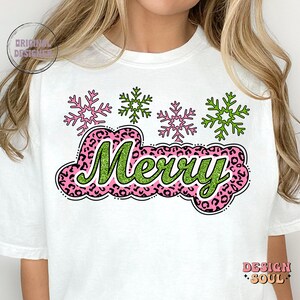 May include: White t-shirt featuring a green and pink "Merry" graphic with a leopard print background. The graphic is surrounded by four pink and green snowflakes.