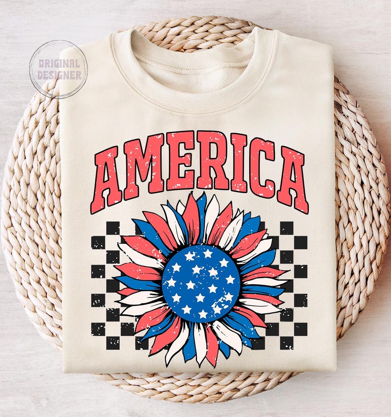 May include: A cream-colored sweatshirt with the word "AMERICA" in red and blue letters. A red, white, and blue sunflower with a checkered background is below the word.