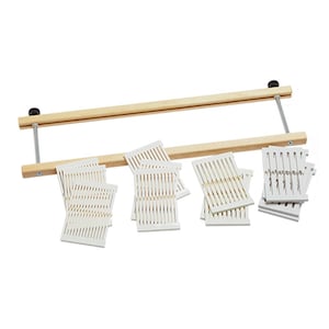 May include: A wooden weaving loom with a light brown finish, featuring a horizontal frame and vertical metal supports. Several white plastic weaving cards are scattered below. The loom is designed for textile crafts.