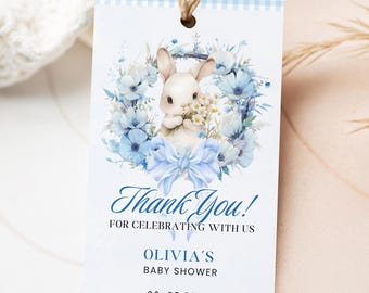 May include: A baby shower gift tag with a blue gingham border. The tag features a watercolor illustration of a white bunny holding flowers, surrounded by blue flowers and a bow. Text reads "Thank You!" and "Olivia's Baby Shower".