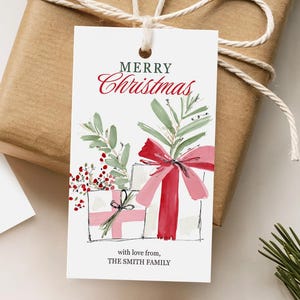 Puede incluir: Dos etiquetas de regalo blancas con ilustraciones de acuarela y el texto "MERRY Christmas" en escritura roja. Una etiqueta presenta patines de hielo con un lazo rojo, la otra tiene regalos y un lazo rojo. Ambas etiquetas incluyen "with love from, THE SMITH FAMILY."