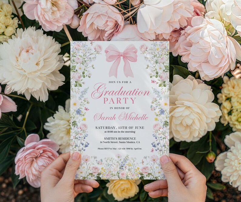 May include: A graduation party invitation with a pink bow and floral border. The invitation reads "Join us for a Graduation Party in Honor of Sarah Michelle." The date is Saturday, June 13th, at 10:00 am. The invitation is held in front of a backdrop of flowers.