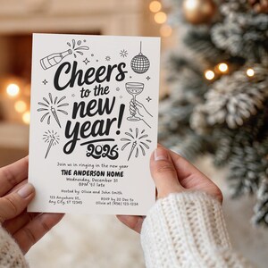 May include: A cream-colored invitation card with black illustrations and text. The card reads "Cheers to the new year! 2026" with fireworks, champagne, and a disco ball graphic. The invitation includes event details for The Anderson Home.