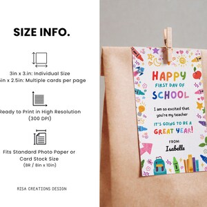 May include: A gift tag with the text "Happy First Day of School" in colorful letters, decorated with school-themed illustrations. The tag is attached to a brown paper bag with a wooden clip. The tag is 3in x 3in.