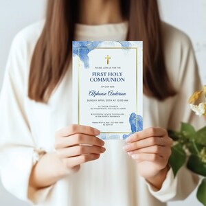 May include: Blue and gold watercolor first communion invitation with a cross and the text "Please join us for the First Holy Communion of our son Alphonse Anderson Sunday April 20th at 10:00 AM St. Peter Church 123 Anywhere St. Any City, ST 12345 Reception Lunch to follow at the Smith's Residence Please RSVP by May 1st 123-456-7890"