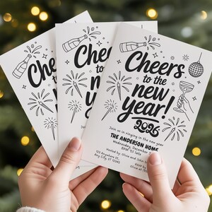 May include: A stack of white New Year's party invitations with black line art illustrations of fireworks, champagne bottles, and a disco ball. The text "Cheers to the new year! 2026" is prominently displayed.