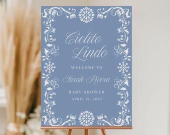 May include: A blue baby shower welcome sign with white floral designs and the text "Cielito Lindo Welcome to Sarah Rivera Baby Shower April 19, 2025".