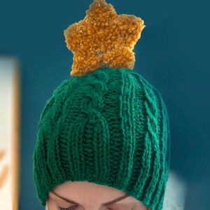 May include: A green knitted hat with a star-shaped pom-pom on top. The pom-pom is made of a fuzzy, golden material.