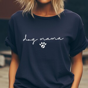 K&ouml;nnte beinhalten: Ein marineblaues T-Shirt mit dem Text "dog mama" in wei&szlig;er Schrift mit einem wei&szlig;en Pfotenabdruck darunter.