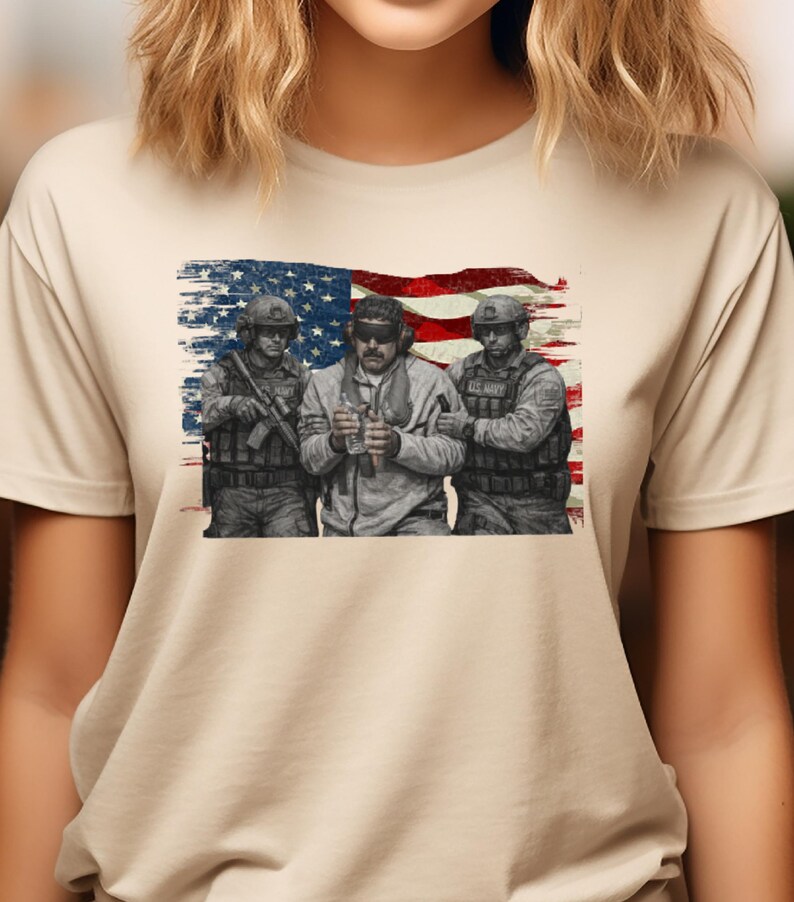 Pode incluir: Camiseta bege com um gr&aacute;fico de tr&ecirc;s soldados em frente a uma bandeira americana desgastada. Os soldados usam equipamento militar e seguram armas. A imagem tem uma est&eacute;tica vintage e patri&oacute;tica.