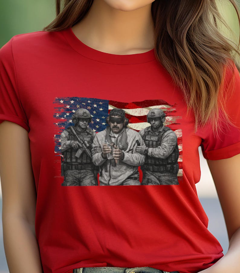 Pode incluir: Camiseta vermelha com uma estampa de tr&ecirc;s soldados em frente a uma bandeira americana desgastada. Os soldados usam equipamento militar. A estampa &eacute; em tons de cinza e preto.