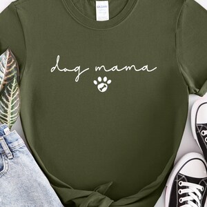 K&ouml;nnte beinhalten: Ein gr&uuml;nes T-Shirt mit dem Text "dog mama" in wei&szlig;en Buchstaben und einem wei&szlig;en Pfotenabdruck.