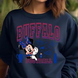 K&ouml;nnte beinhalten: Marineblaues Sweatshirt mit dem Text "BUFFALO FOOTBALL" in Rot und Blau. Minnie Mouse mit einer blauen Schleife mit Punkten ist abgebildet. Football-Grafiken sind ebenfalls zu sehen.