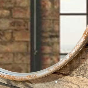 47cm diameter industrial style round mirror hanging on wall by its jute rope hanger, the frame is made from metal and finished in a rustic silver.