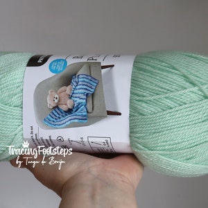 May include: A skein of light green yarn with a label that says "Tracing Footsteps by Tanja de Bruijn".