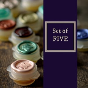 May include: A collection of five wax seal bottle stoppers with various colors, including green, copper, and blue. Each stopper has a unique embossed design. The text "Set of FIVE" is displayed in a framed box.