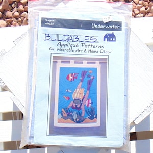 May include: A blue and white package with the text "Buildables Applique Patterns for Wearable Art & Home Decor" and a picture of a woman scuba diving. The package is for a craft project titled "Underwater" and has the project number WH280.