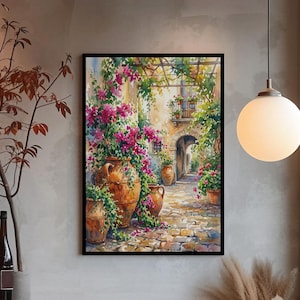 May include: A framed watercolor painting depicts a sunlit Italian courtyard. Terracotta pots overflow with vibrant pink flowers and green foliage. A stone pathway leads to an arched doorway, creating a sense of depth and tranquility. The artwork is displayed in a cozy, well-lit interior.