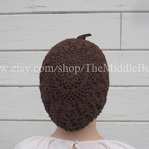 Può includere: Una rete per capelli in crochet marrone con un piccolo nastro marrone in cima.