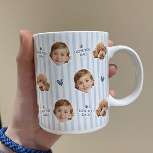May include: White ceramic mug with a blue striped pattern. The mug features images of a child and a dog, along with the text "I LOVE YOU DAD". A blue woven bracelet is visible in the foreground.